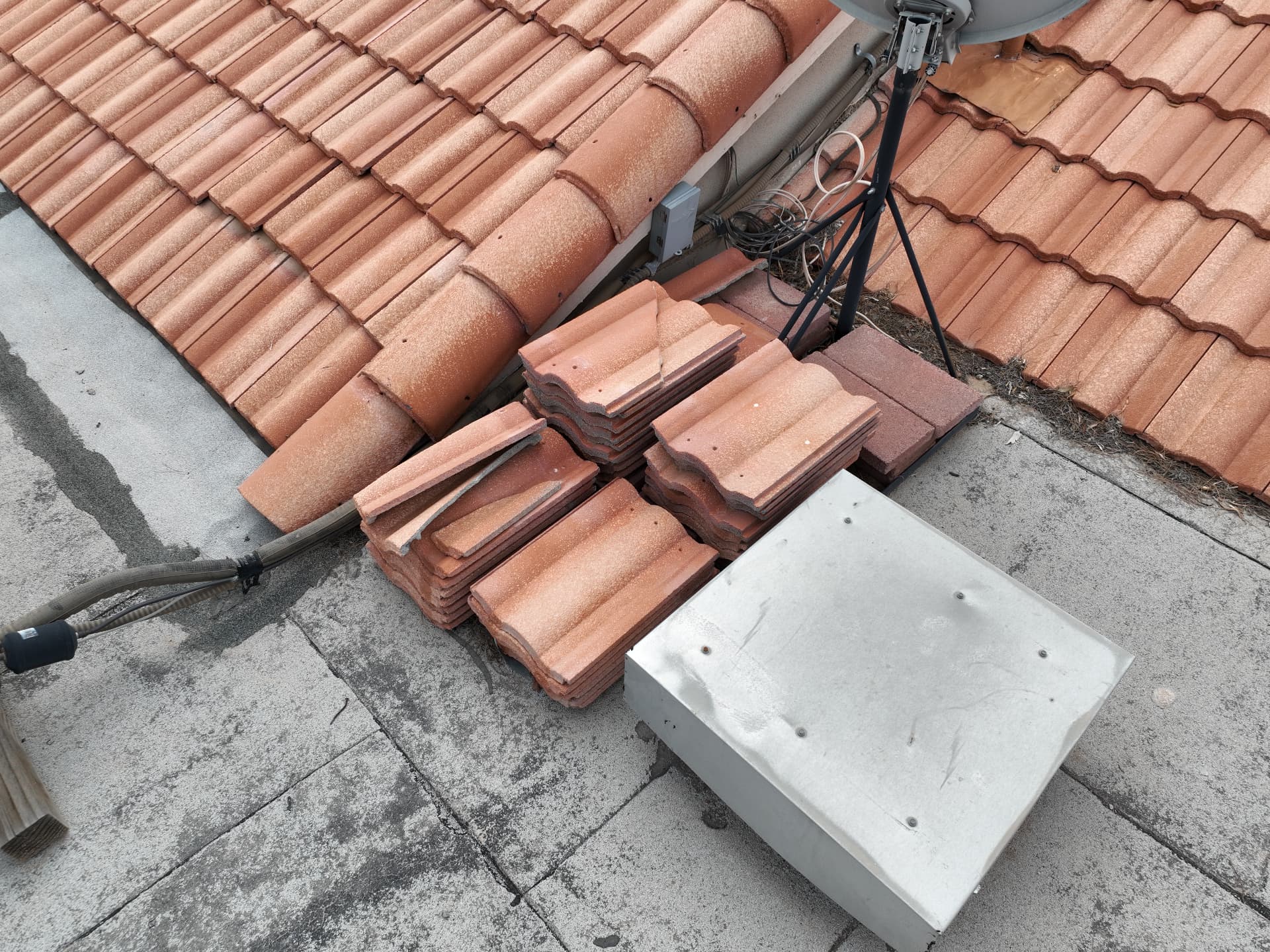 Stacked concrete roof tile and satellite mast on a Chandler AZ 85249 tile roof before replacement