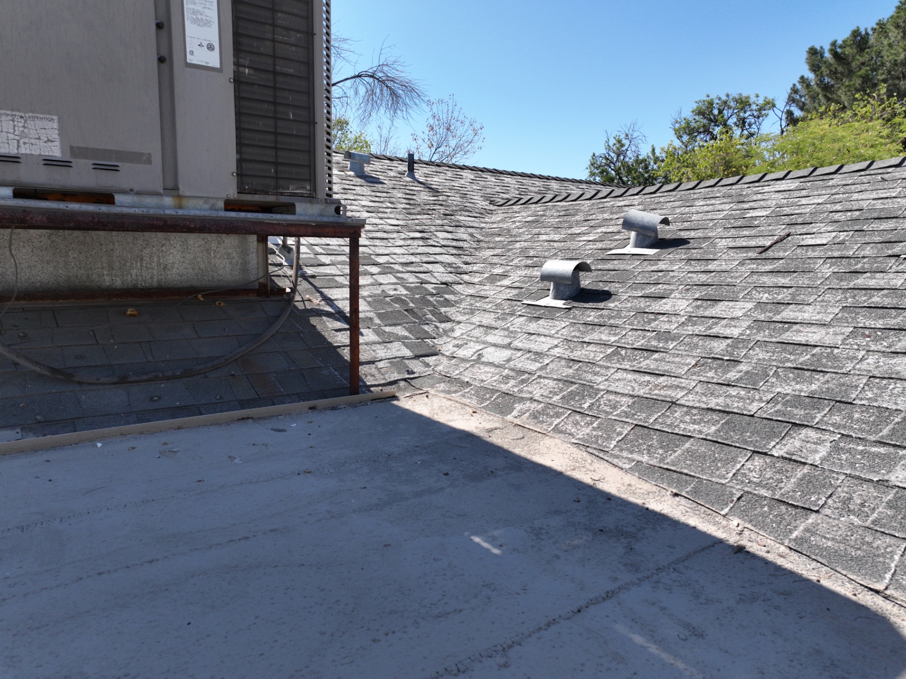 HVAC unit at transition between shingle roof and coated flat roof section