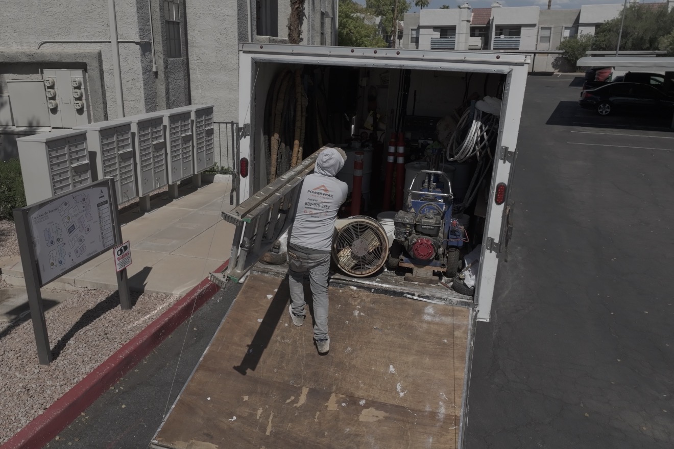 Power Peak Roofing crew member unloading a ladder from an equipment trailer at a Scottsdale AZ condominium