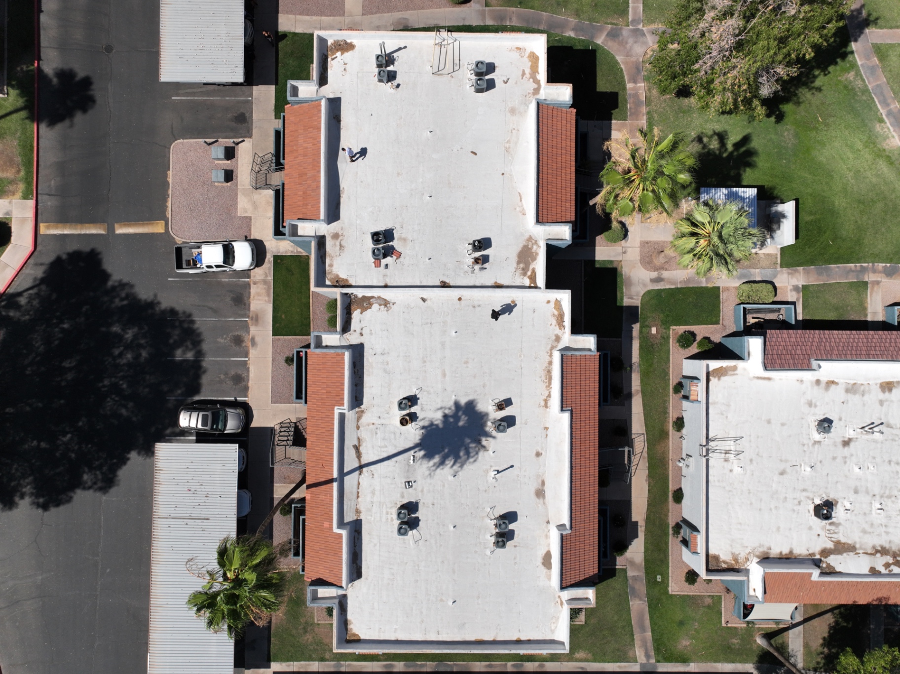 Top-down drone view of two apartment buildings in Chandler AZ with degraded white foam roofs