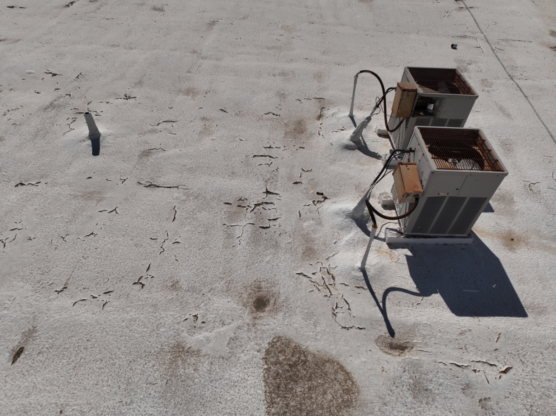 Close-up of foam roof damage showing UV alligator cracking and blistering on Chandler AZ apartment building