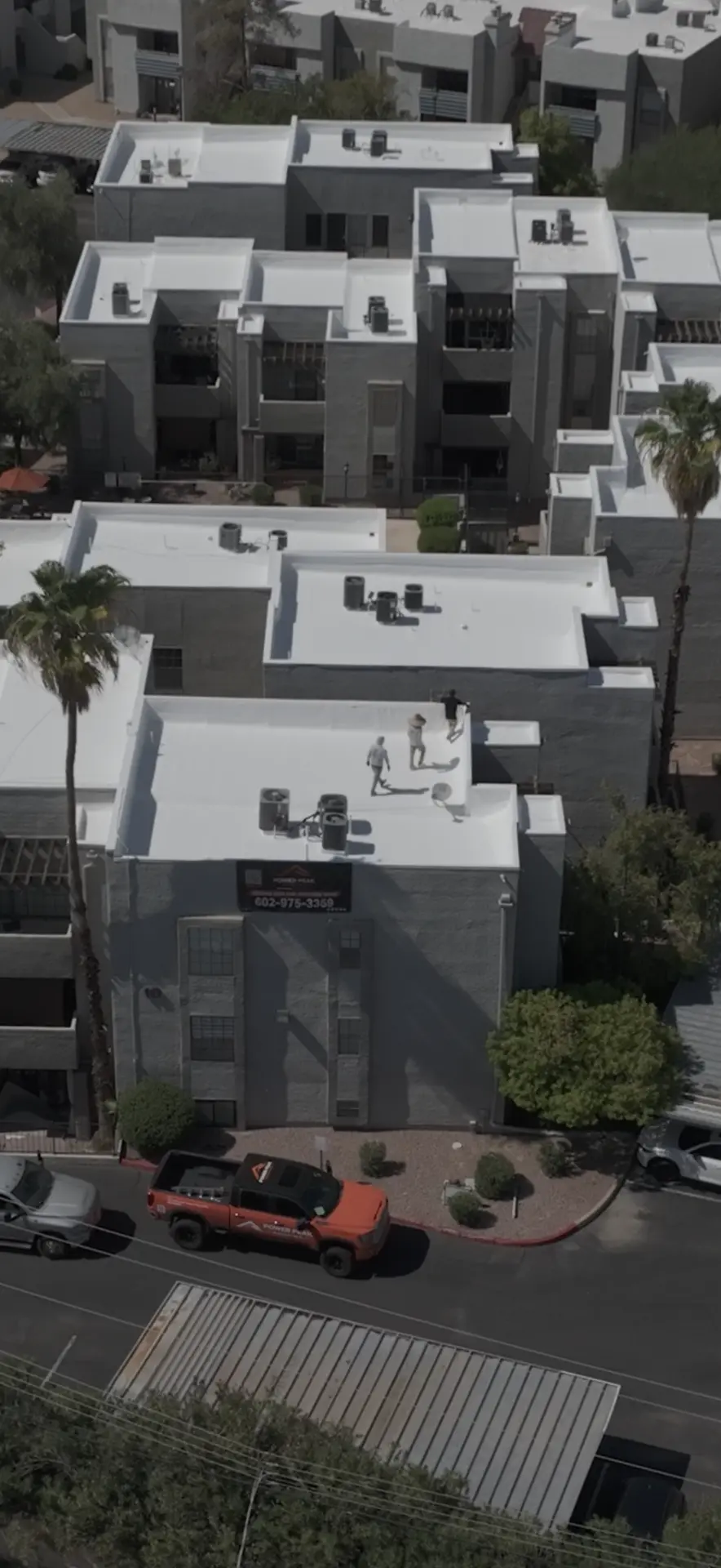 Aerial view of roofers finishing elastomeric coating on a condominium building in Scottsdale AZ