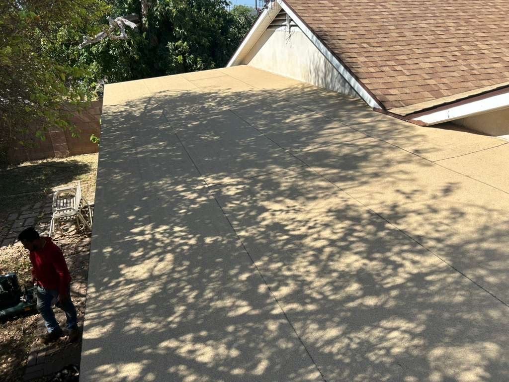 Completed low-slope roof section on Mesa home with fresh tan coating