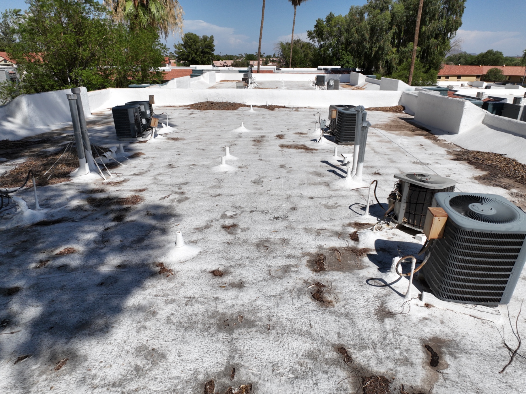 Rooftop view of weathered spray foam roof with AC units on Chandler AZ apartment building