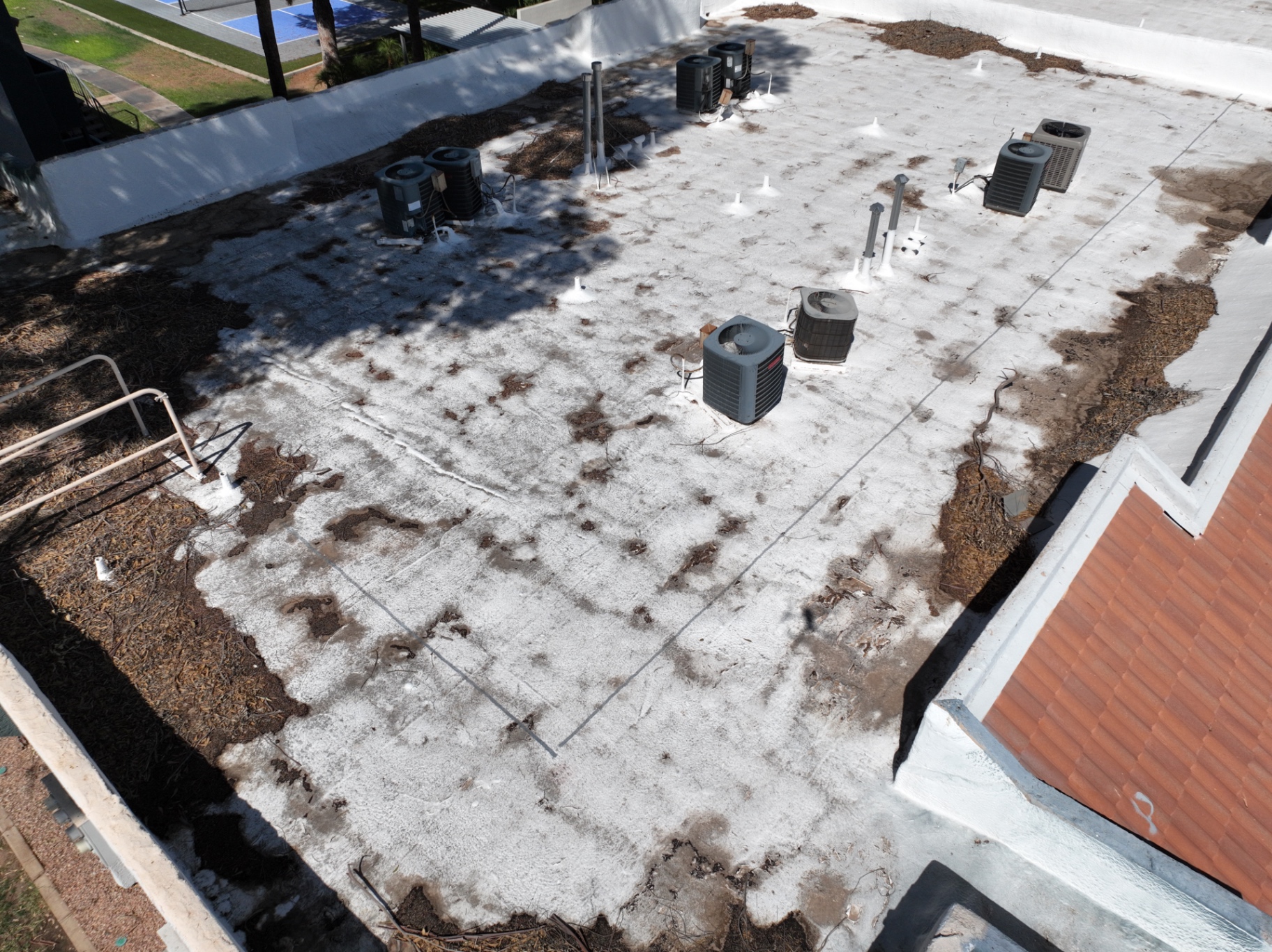 Severely degraded foam roof coating with heavy debris on Chandler apartment complex