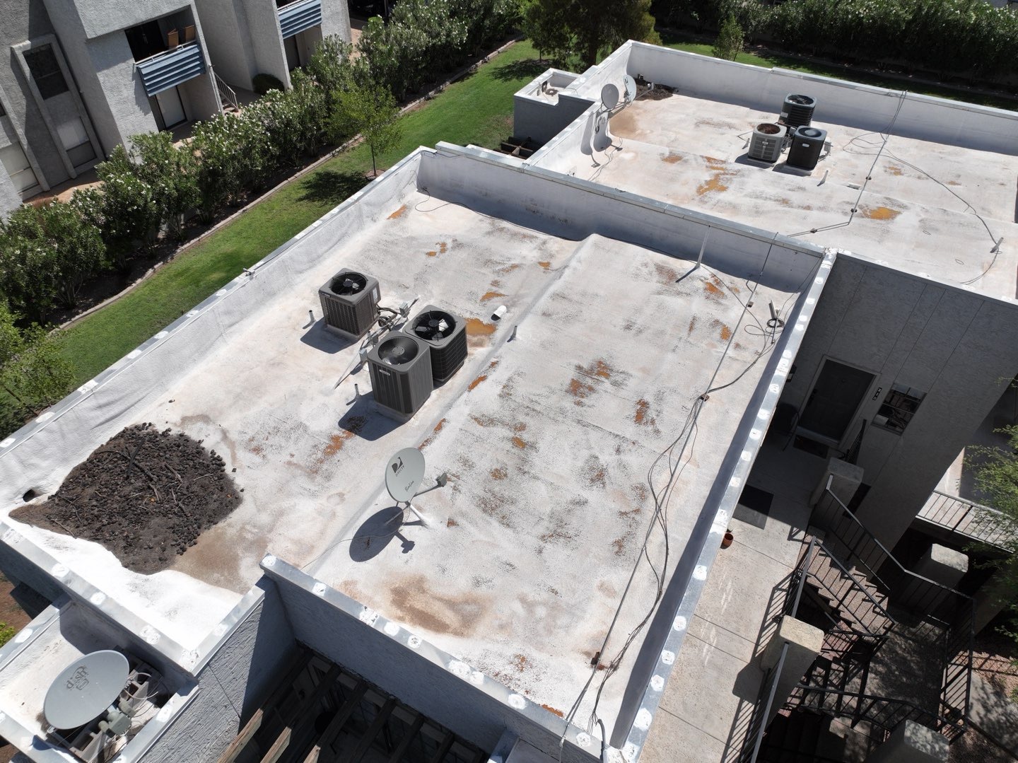 Aerial view of aging condominium roofs with HVAC units and satellite dishes in Scottsdale AZ